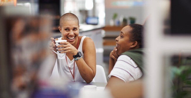 Two women drinking coffee and laughing